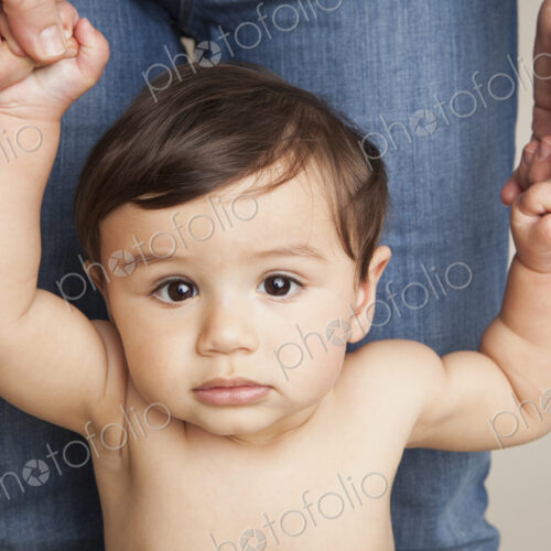 An 8 month old baby boy holding his parent's hands and balancing upright. An 8 month old baby boy holding his parent's hands and balancing upright.
