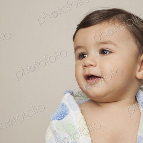 An 8 month old baby boy with a bath towel wrapped around him. An 8 month old baby boy with a bath towel wrapped around him.