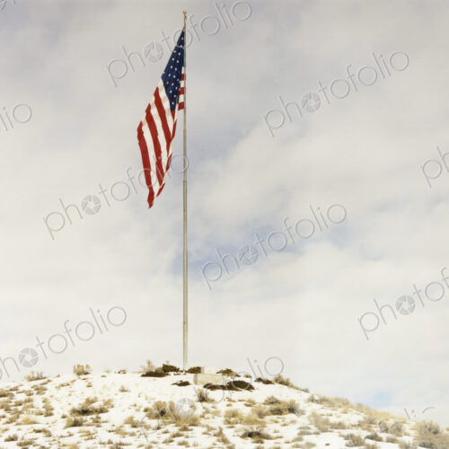 An American flag Stars and Stripes, flying from a flagpole on a small hillock.