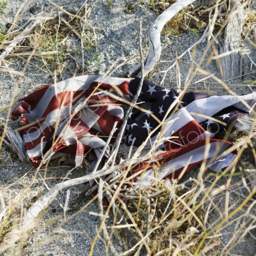 An American flag, crumpled up on the sandy ground, damaged, An American flag, crumpled up on the sandy ground, damaged,