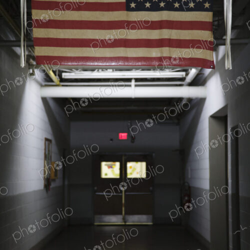 An American flag, the stars and stripes hanging in a public place, in a corridor. An American flag, the stars and stripes hanging in a public place, in a corridor.