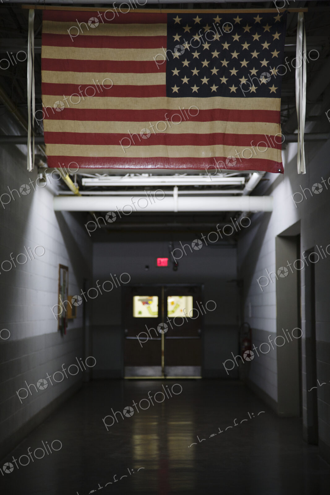 An American flag, the stars and stripes hanging in a public place, in a corridor.