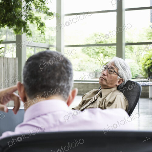 An Asian businessman and Caucasian businessman working on laptop computer An Asian businessman and Caucasian businessman working on laptop computer