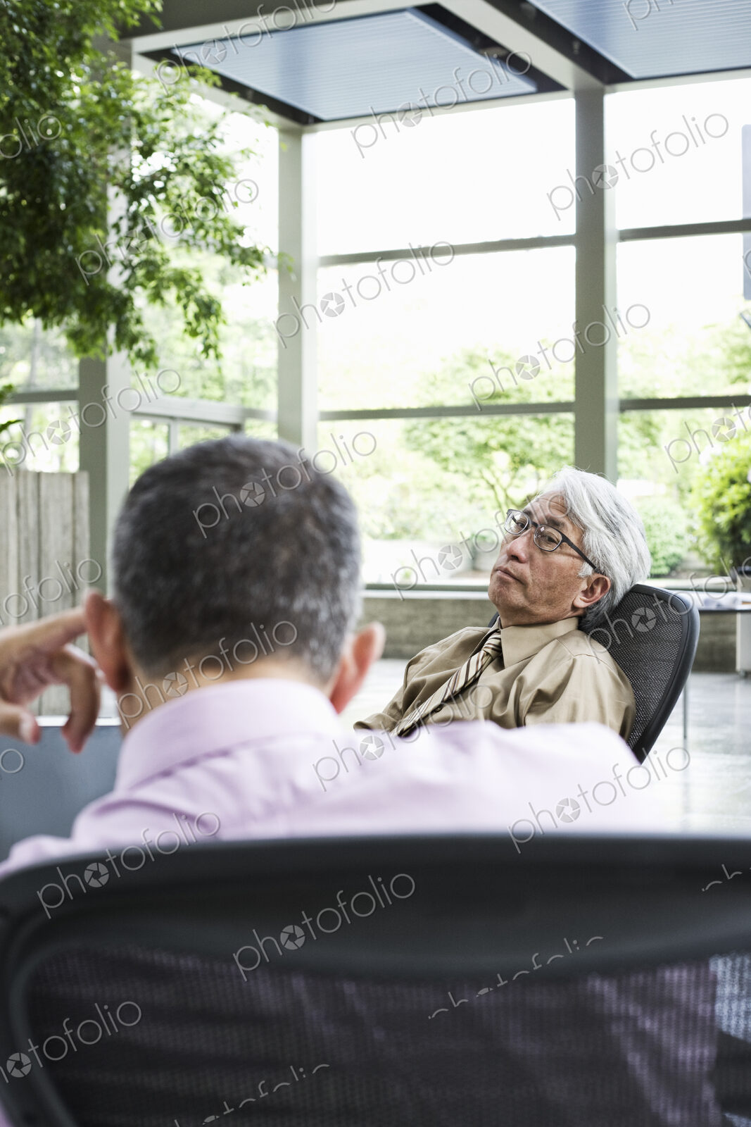 An Asian businessman and Caucasian businessman working on laptop computer