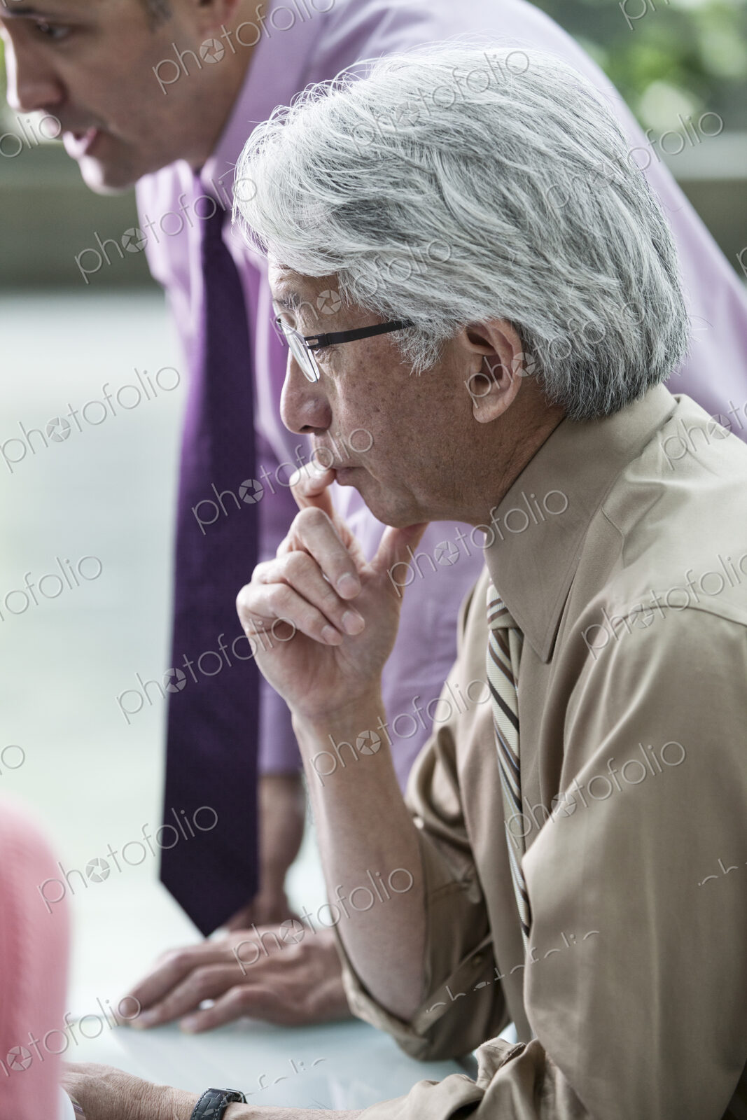 An Asian businessman and Caucasian businessman working on laptop computer