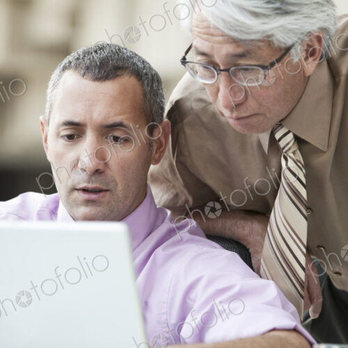 An Asian businessman and Caucasian businessman working on laptop computer An Asian businessman and Caucasian businessman working on laptop computer
