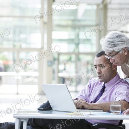An Asian businessman and Caucasian businessman working on laptop computer An Asian businessman and Caucasian businessman working on laptop computer
