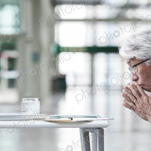An Asian businessman ponders a problem on his laptop computer at his desk. An Asian businessman ponders a problem on his laptop computer at his desk.