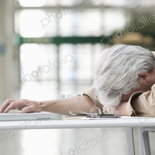 An Asian businessman ponders a problem on his laptop computer at his desk. An Asian businessman ponders a problem on his laptop computer at his desk.