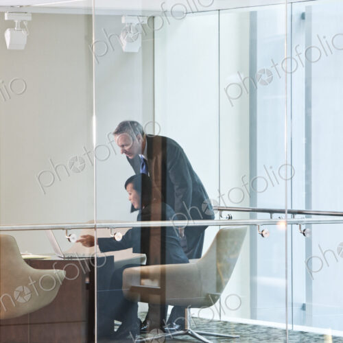 An Asian businesswoman and a caucasian businessman at work at a conference table. An Asian businesswoman and a caucasian businessman at work at a conference table.