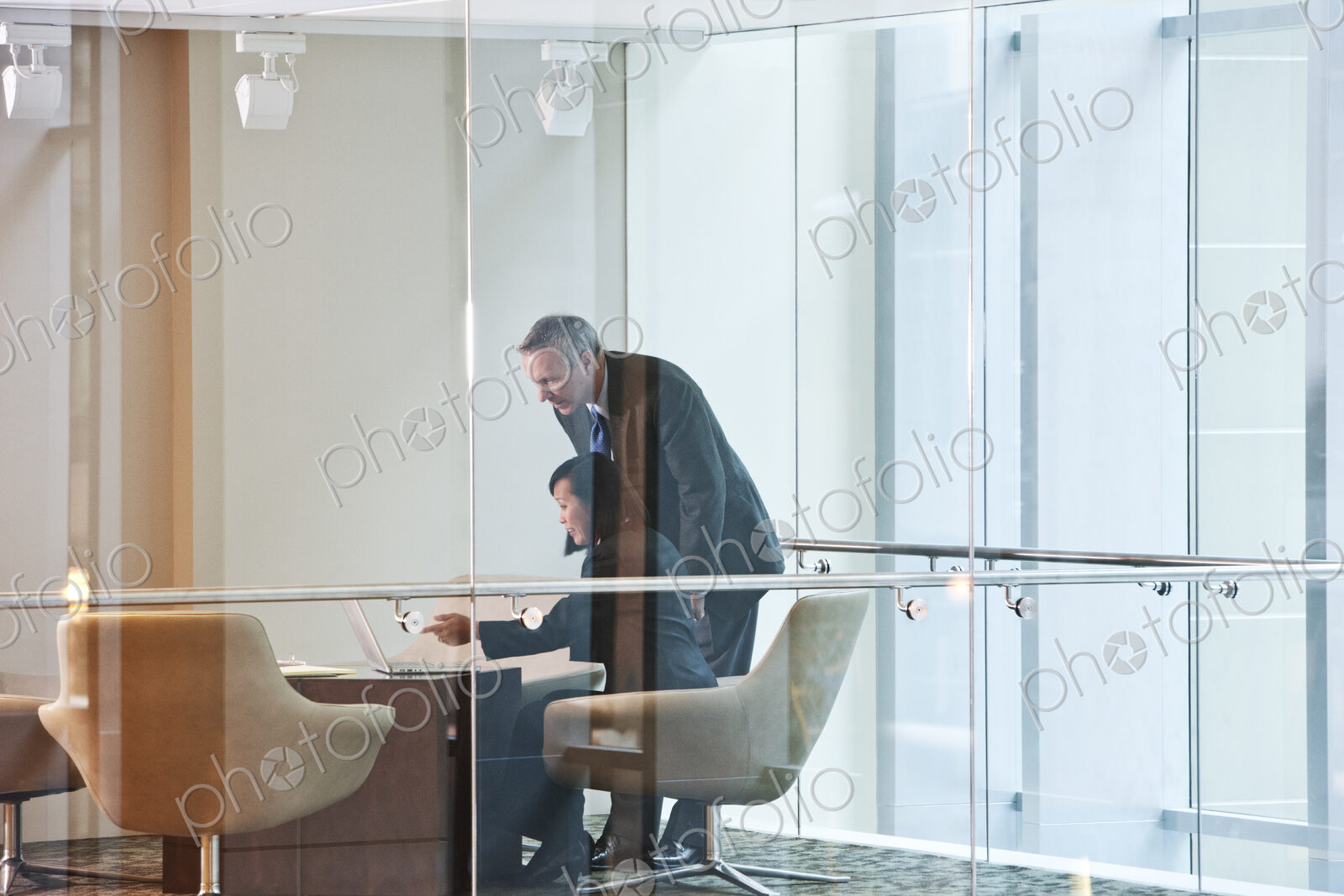 An Asian businesswoman and a caucasian businessman at work at a conference table.