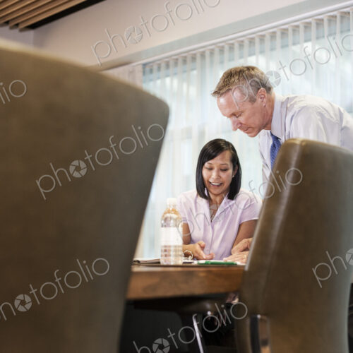 An Asian businesswoman and a caucasian businessman at work at a conference table. An Asian businesswoman and a caucasian businessman at work at a conference table.