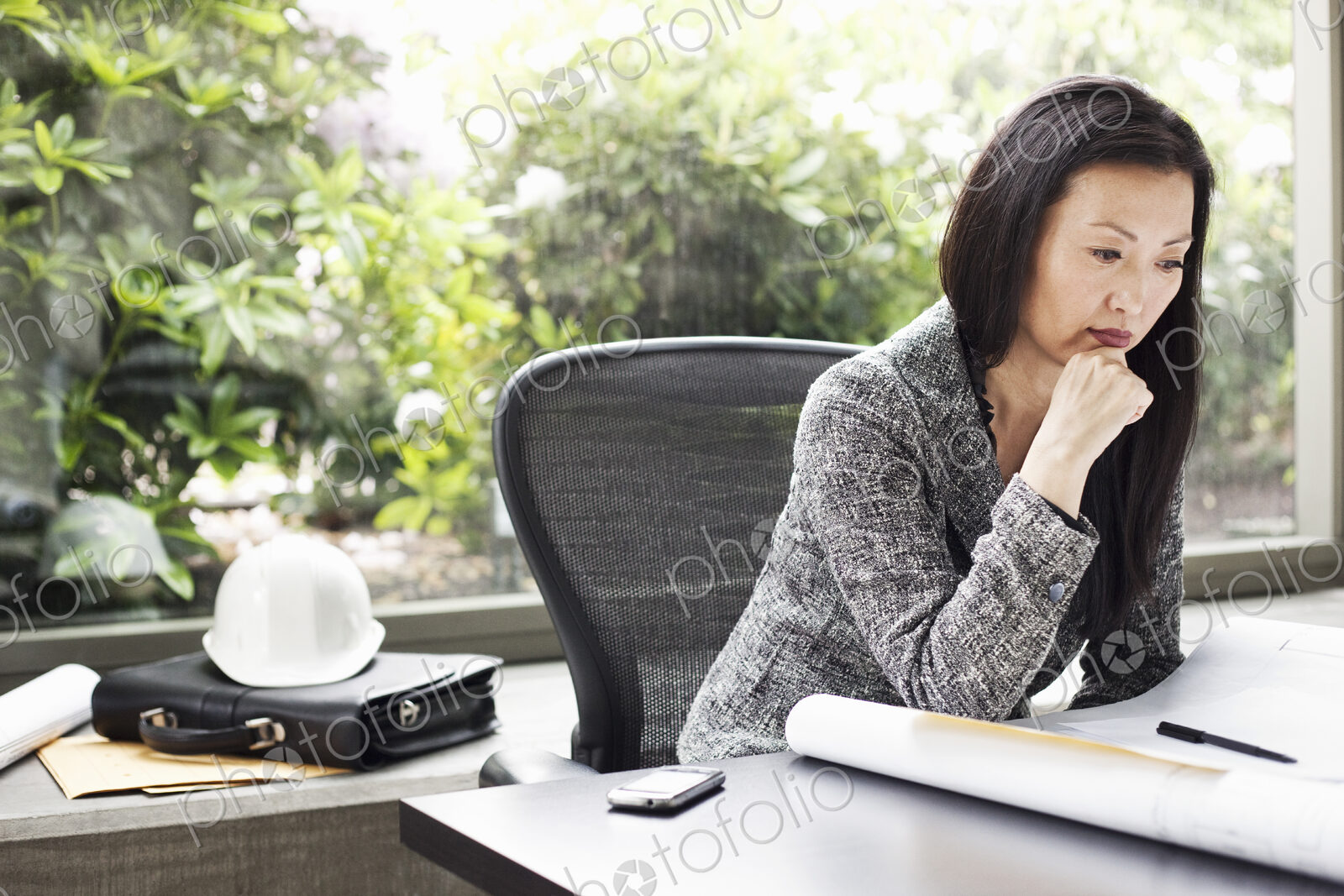An Asian businesswoman working on architectural plans in her busiess office.
