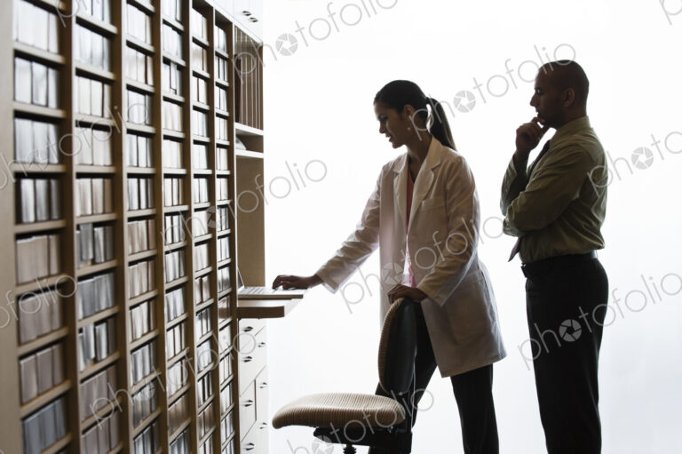 An Hispanic female dentist and a Middle Eastern dentist looking at a computer in their…