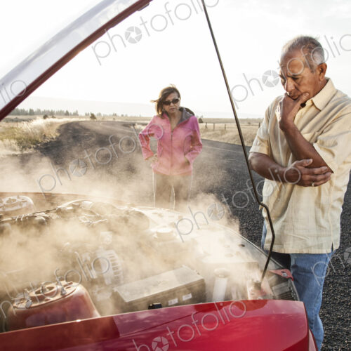 An Hispanic senior couple pulled over at the side of the road with engine trouble. An Hispanic senior couple pulled over at the side of the road with engine trouble.