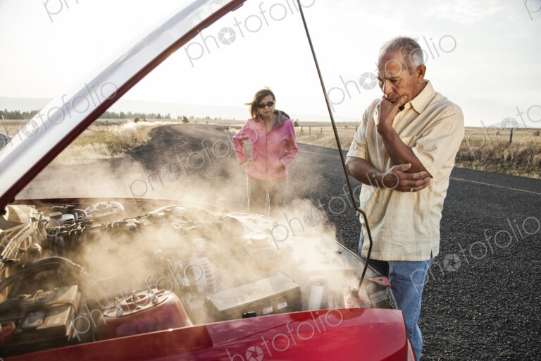 An Hispanic senior couple pulled over at the side of the road with engine trouble.