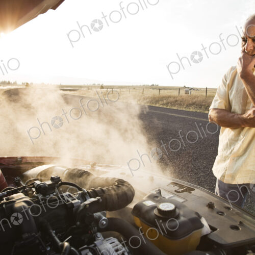 An Hispanic senior man pulled over at the side of the road with engine trouble.