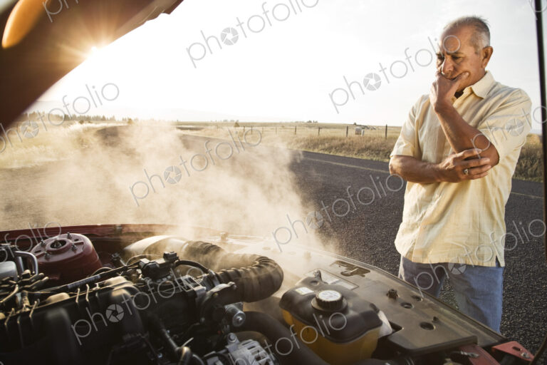 An Hispanic senior man pulled over at the side of the road with engine trouble.