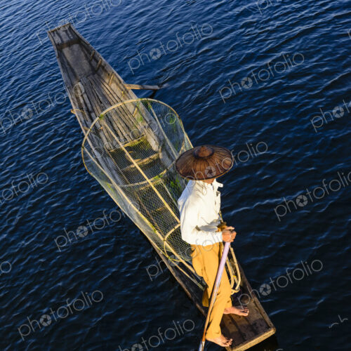 An Intha fisherman on Lake Inle on a traditional boat ith fishing nets, overhead view.