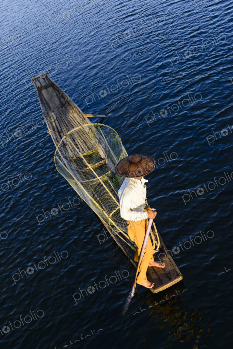 An Intha fisherman on Lake Inle on a traditional boat ith fishing nets, overhead view.