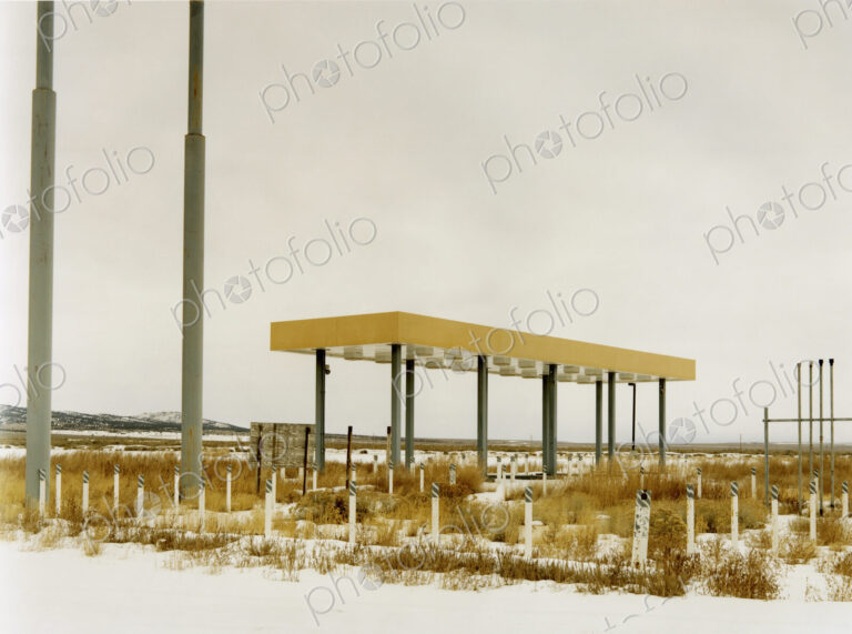 An abamdoned gas station, petrol station in the middle of nowhere, plants growing over…