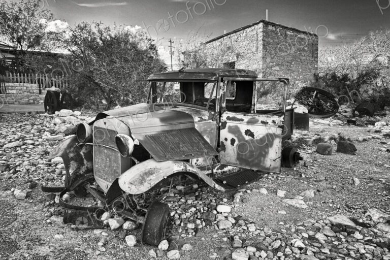 An abandoned classic vintage motor car, with rusting bent metal, no windows and bare…