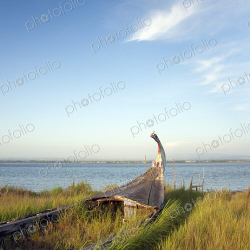 An abandoned wooden moliceiros fishing boat on the dunes overlooking the sea.