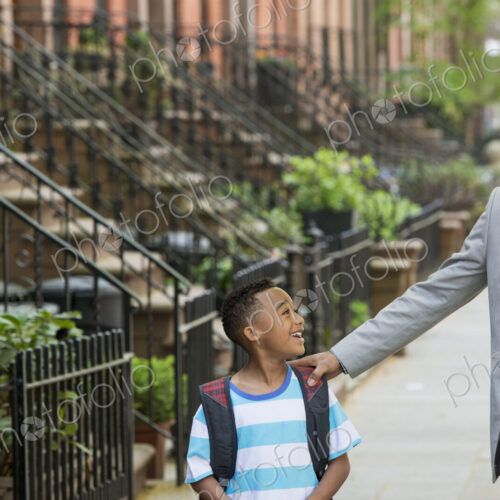 An adult and a child, a father and son, walking together on the street in the city. An adult and a child, a father and son, walking together on the street in the city.
