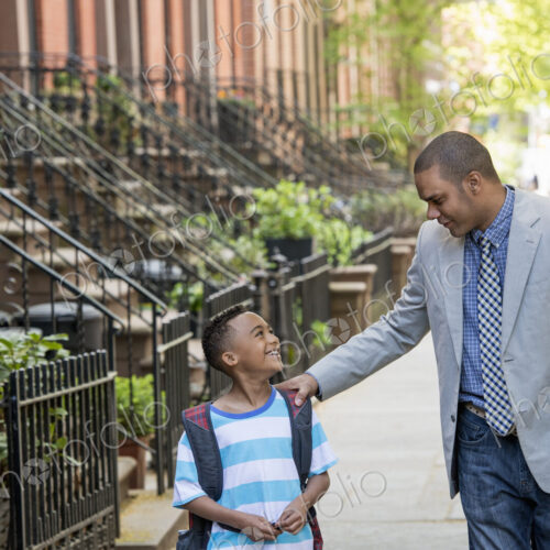 An adult and a child, a father and son, walking together on the street in the city. An adult and a child, a father and son, walking together on the street in the city.