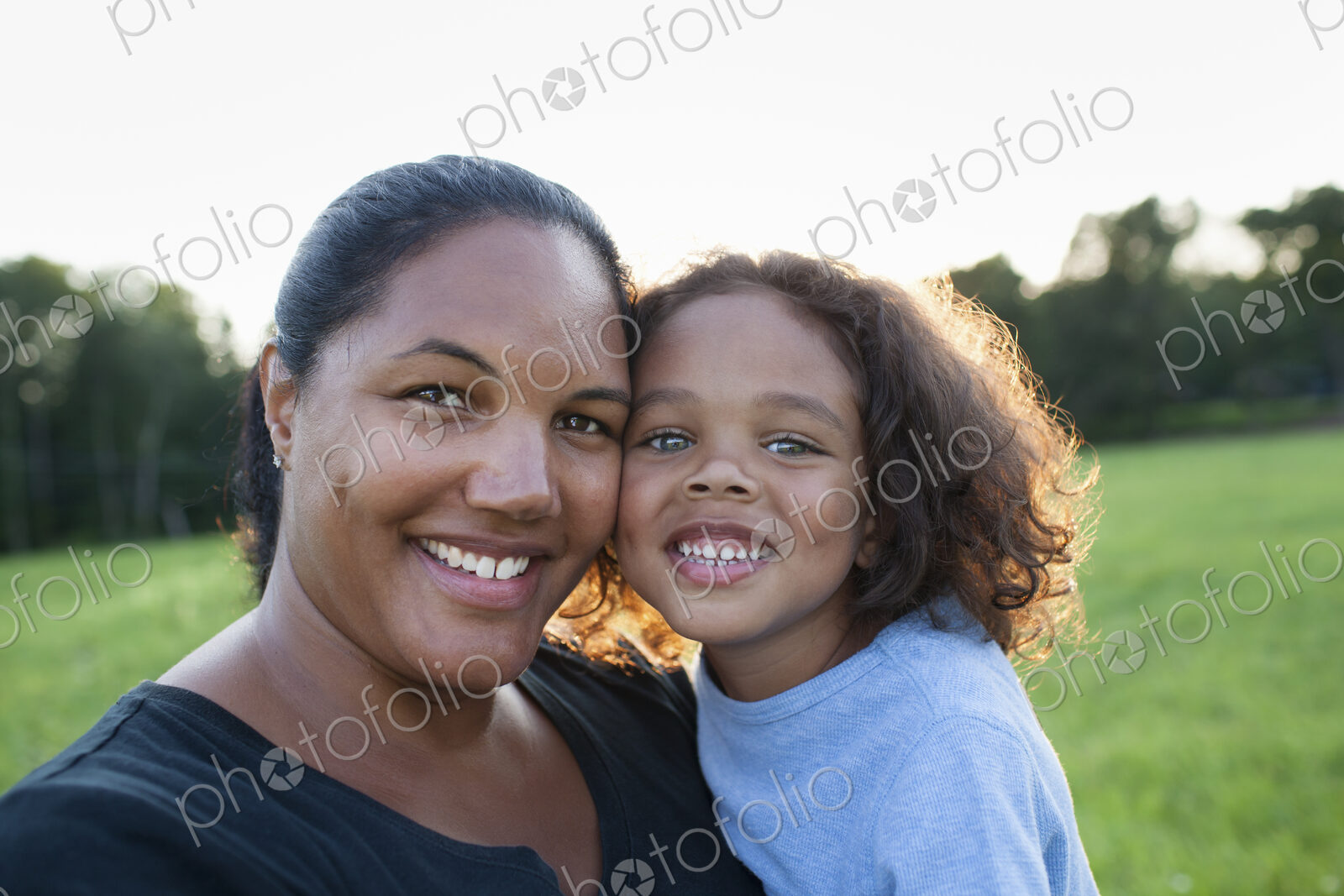 An adult woman and a child, mother and son, outdoors in evening light.