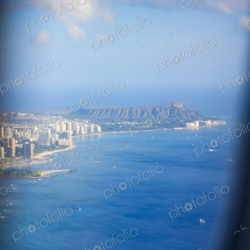 An aerial view over Waikiki Beach, the volcanic landscape of Diamond Head, the…