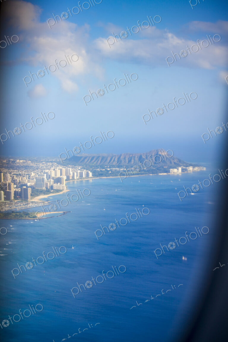 An aerial view over Waikiki Beach, the volcanic landscape of Diamond Head, the…