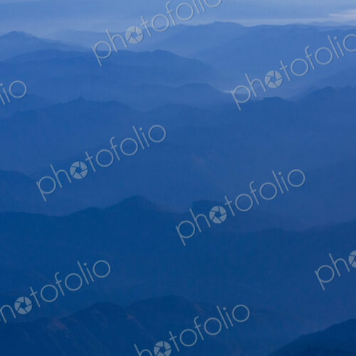 An aerial view over the mountains of the Cascade Range, blue misty colours and sky.
