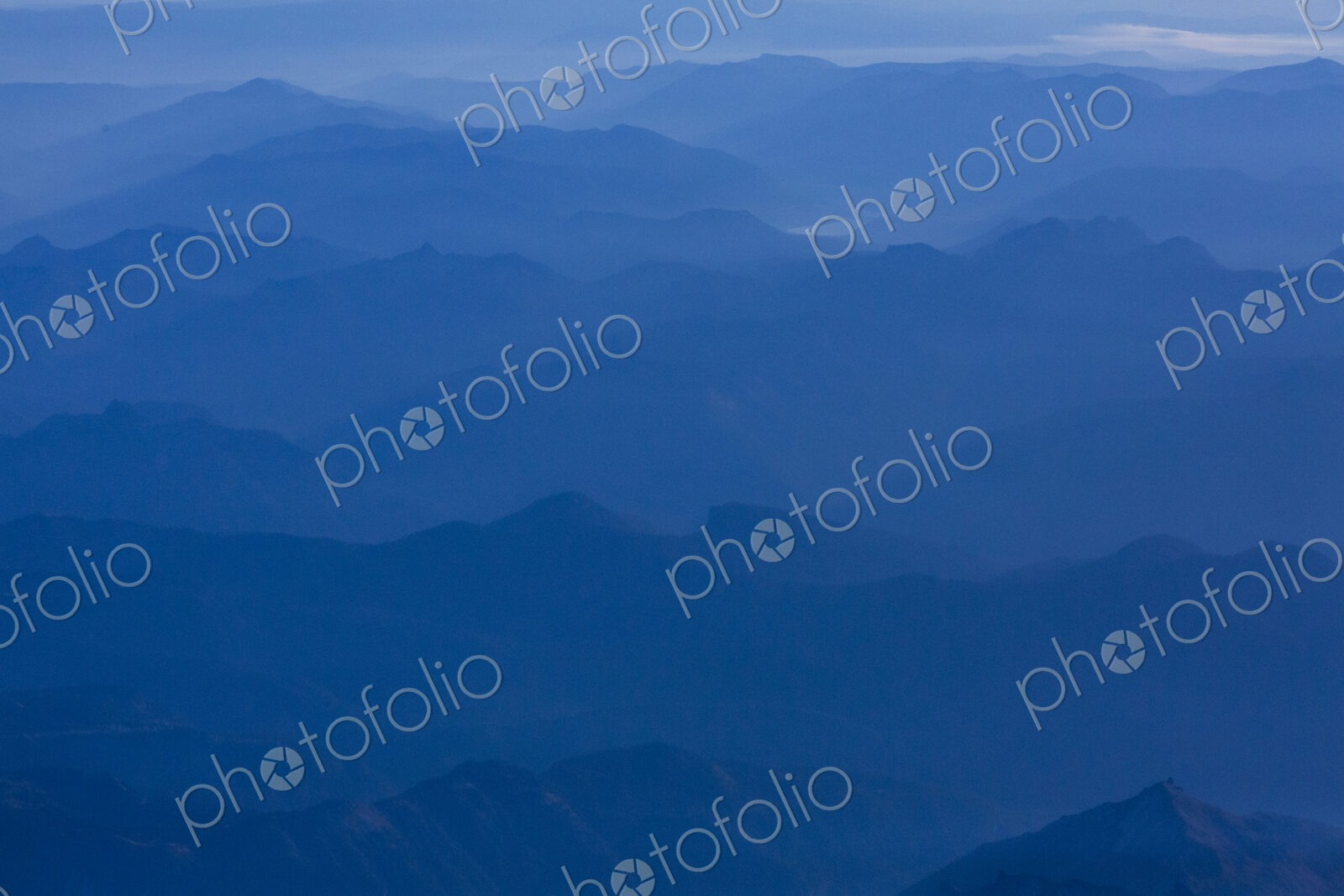 An aerial view over the mountains of the Cascade Range, blue misty colours and sky.