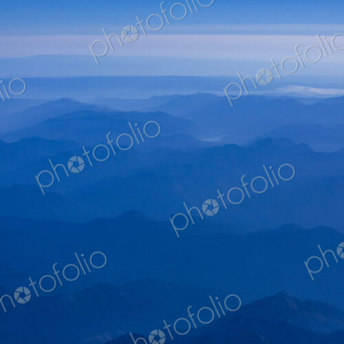 An aerial view over the mountains of the Cascade Range, blue misty colours and sky.
