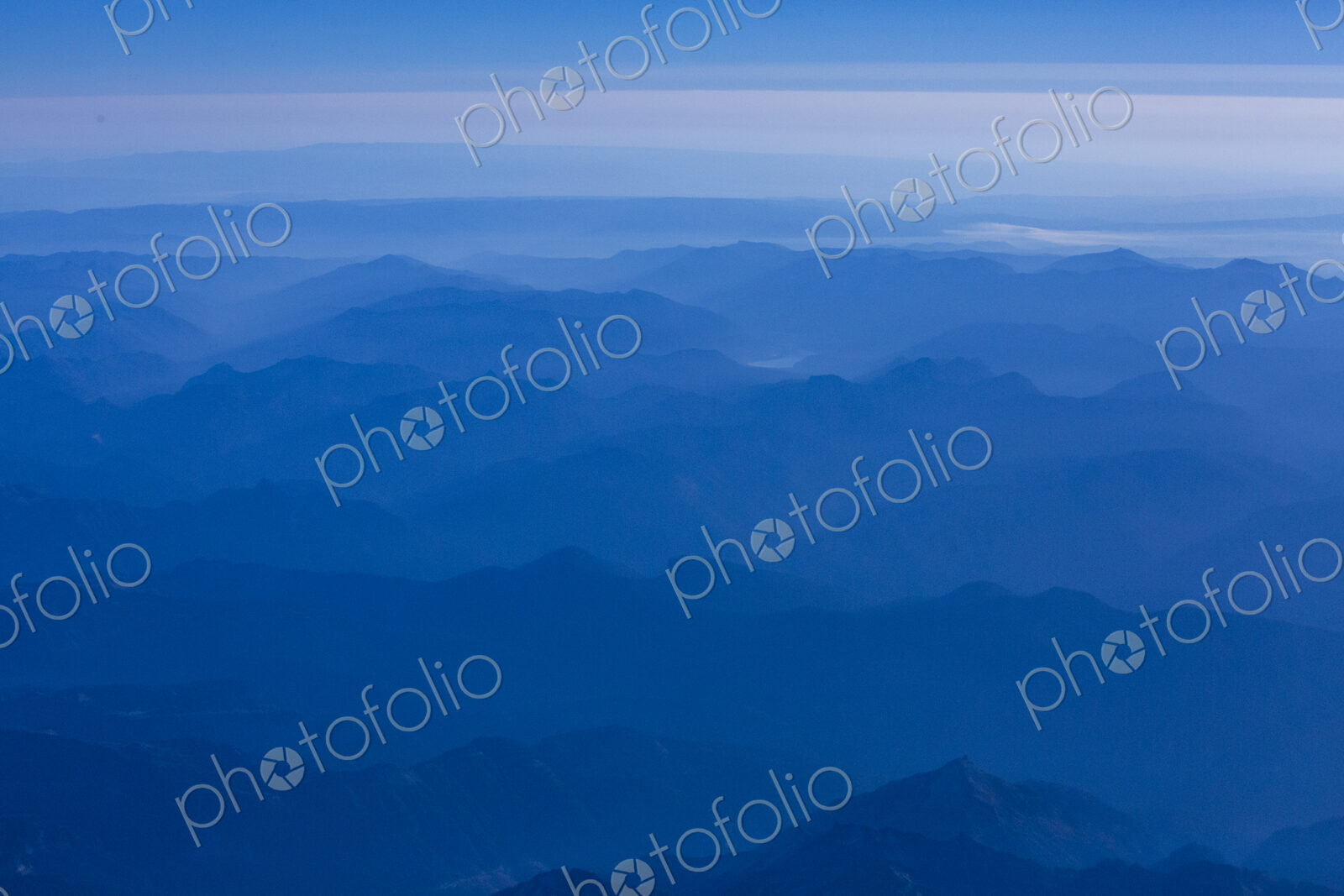 An aerial view over the mountains of the Cascade Range, blue misty colours and sky.