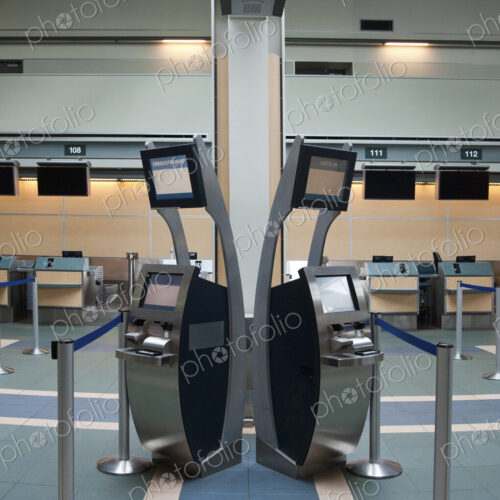 An airport check in area, closed desk and self check in terminals.