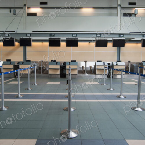 An airport check in area, closed desks and empty wait line queuing spaces.