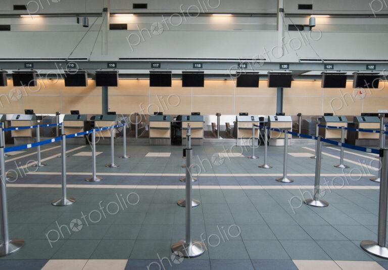 An airport check in area, closed desks and empty wait line queuing spaces.
