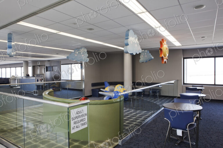 An airport departure lounge children's play area with signs. Tables and chairs.