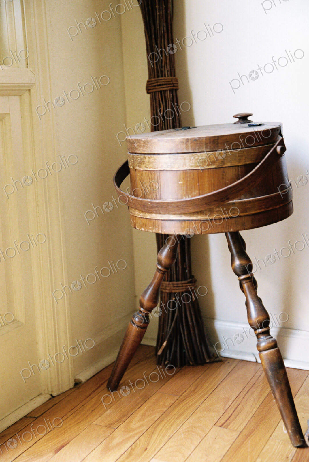 An antique object, a three legged ice box or container in the corner of a room.