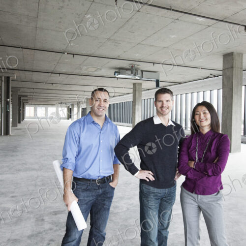 An architect and two owners of a new raw business space standing in a line.