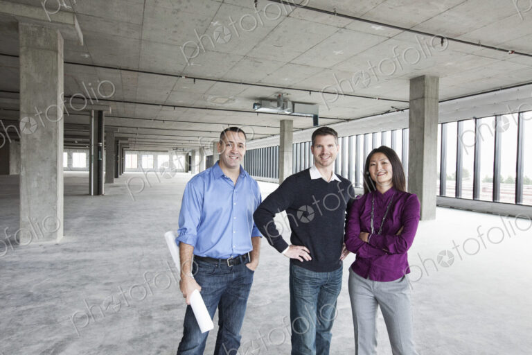 An architect and two owners of a new raw business space standing in a line.