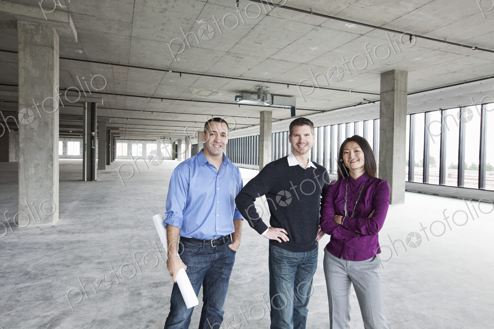An architect and two owners of a new raw business space standing in a line.