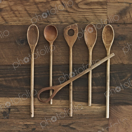 An arrangement of six wooden spoons of a variety of shapes and sizes on a wooden table. An arrangement of six wooden spoons of a variety of shapes and sizes on a wooden table.