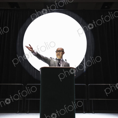 An asian businesman standing at a podium giving a talk at a convention. An asian businesman standing at a podium giving a talk at a convention.