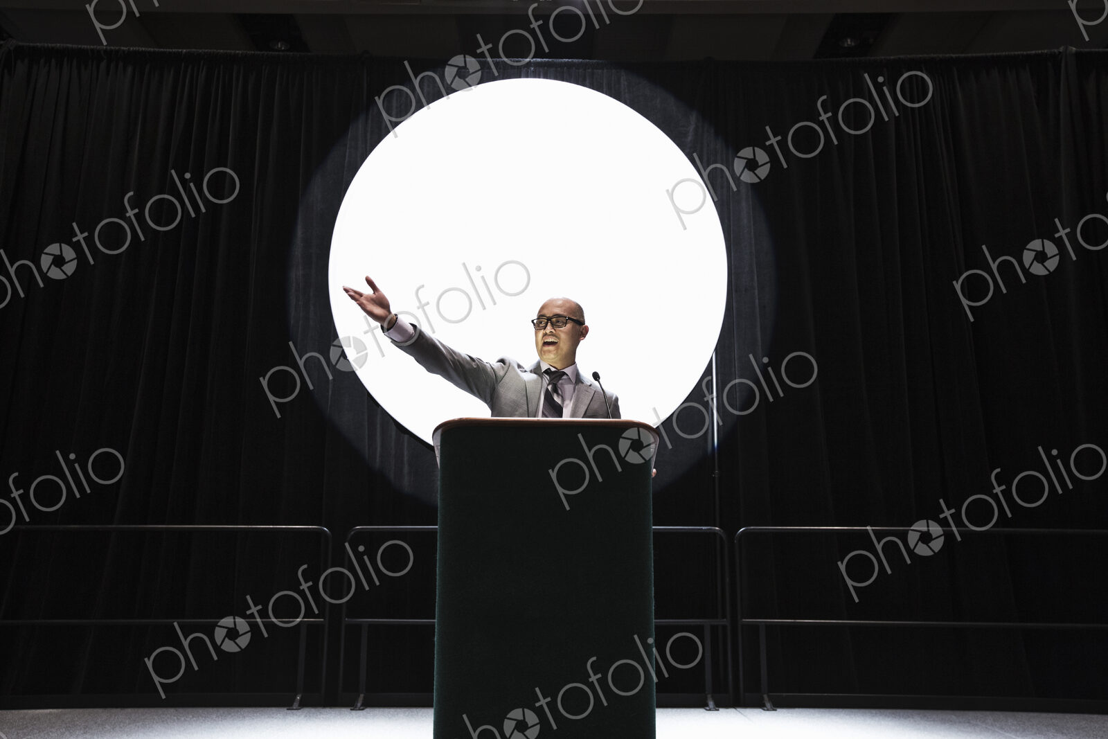An asian businesman standing at a podium giving a talk at a convention.