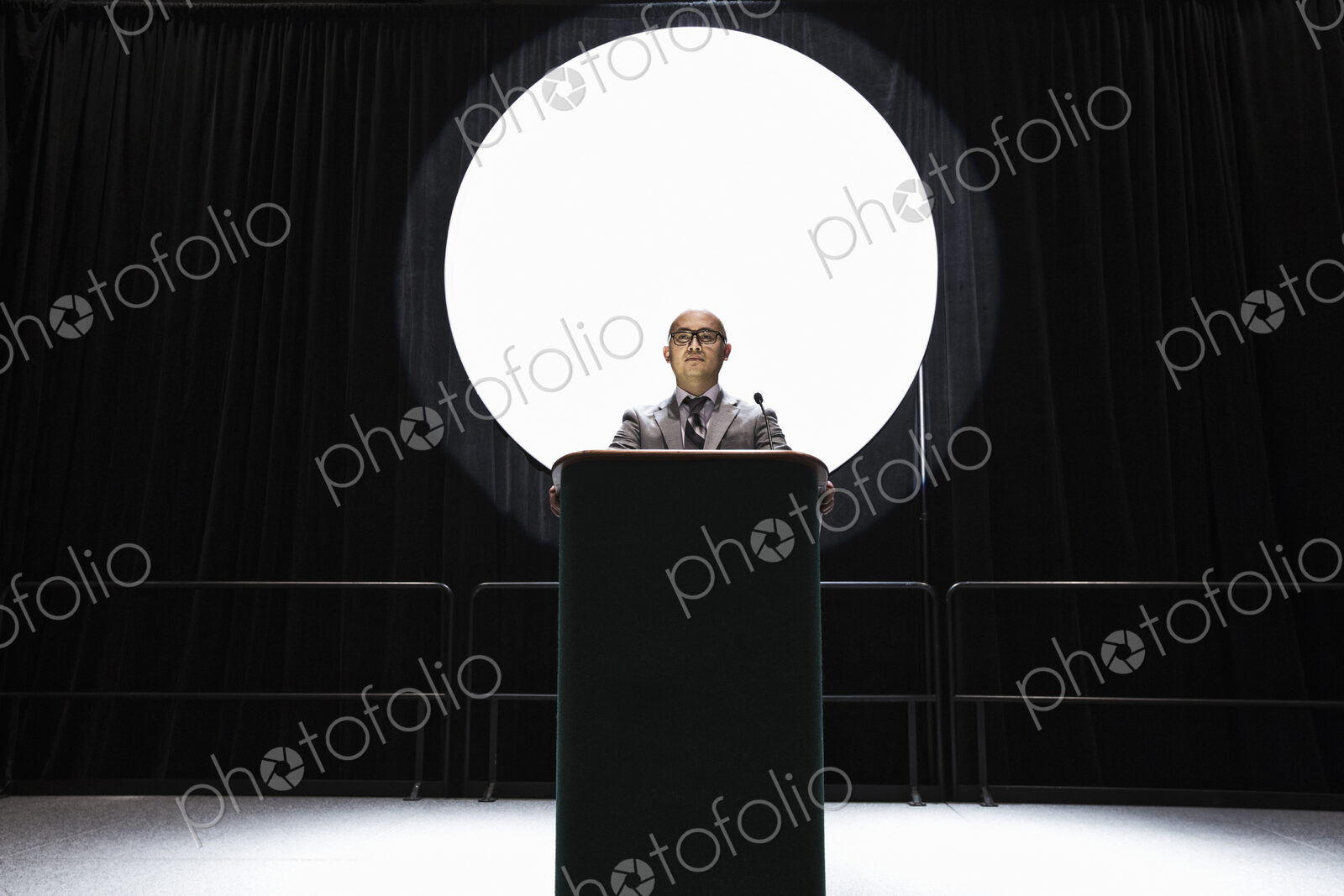 An asian businesman standing at a podium giving a talk at a convention.