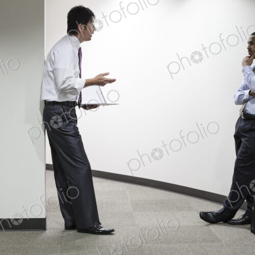 An asian businessman and a black businessman talking over an issue in an office