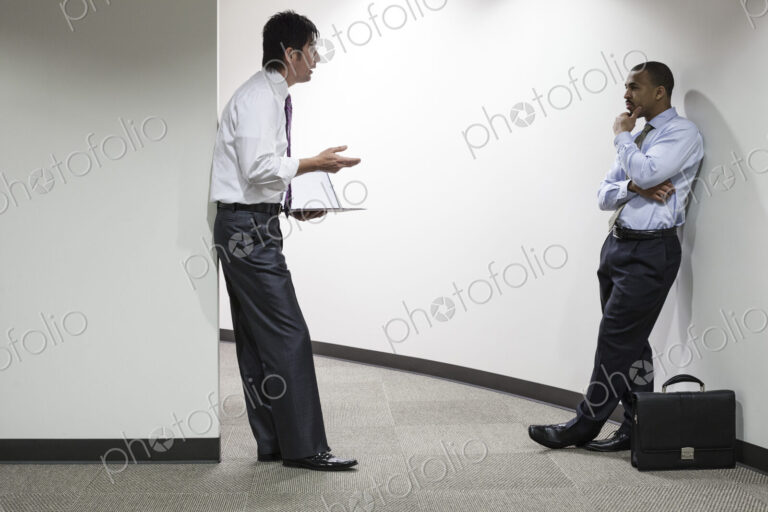 An asian businessman and a black businessman talking over an issue in an office